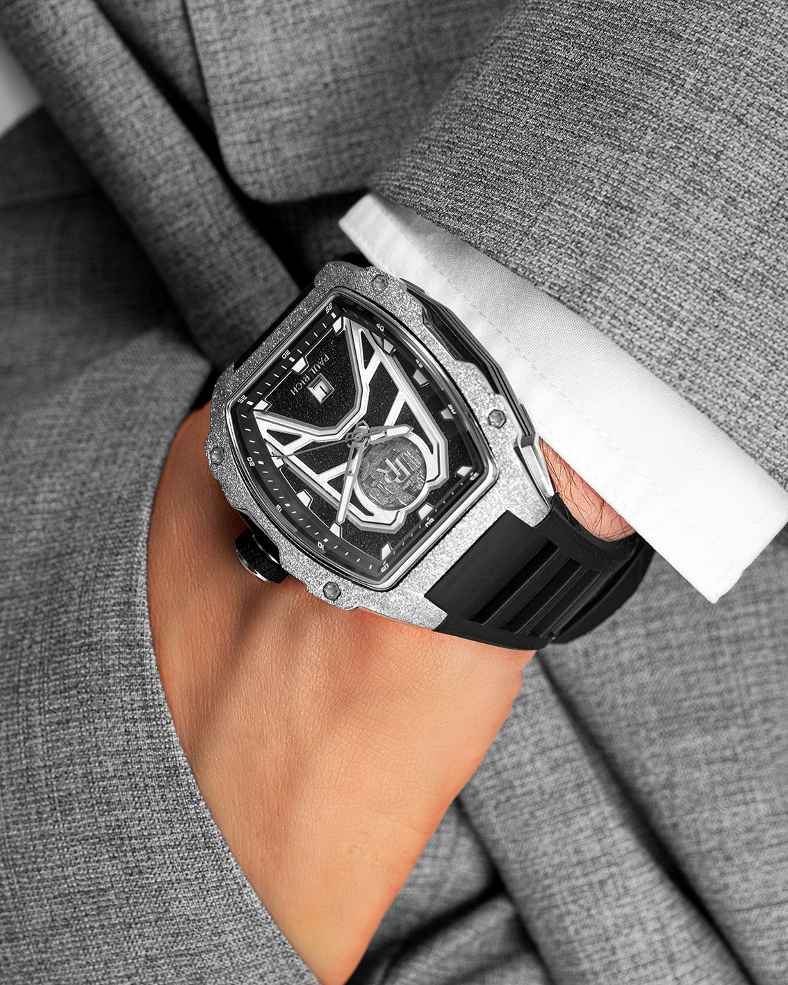 Paul Rich Astro Meteora with frosted silver bezel and meteorite inlay, worn with a grey suit and white cuff, hand tucked into pocket.