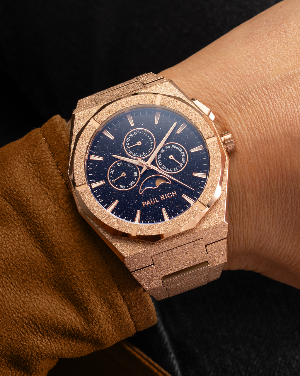 Frosted rose gold moonphase watch on wrist with aventurine dial, calendar subdials, and shimmering textured rose gold bracelet.