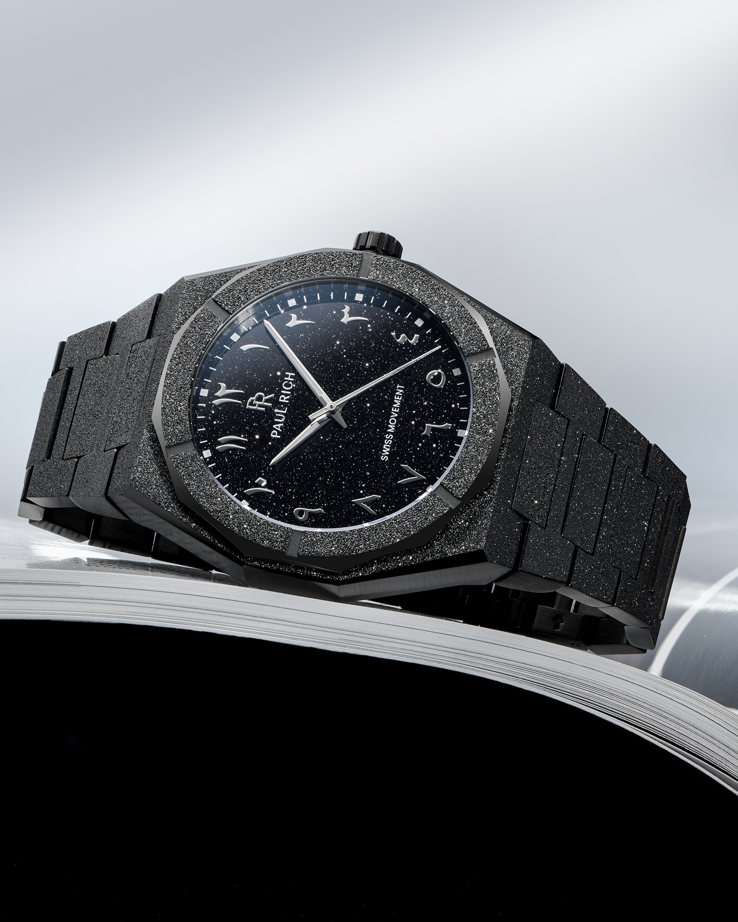 Paul Rich frosted black watch with black aventurine dial and silver Arabic numerals, displayed on the edge of an open magazine.