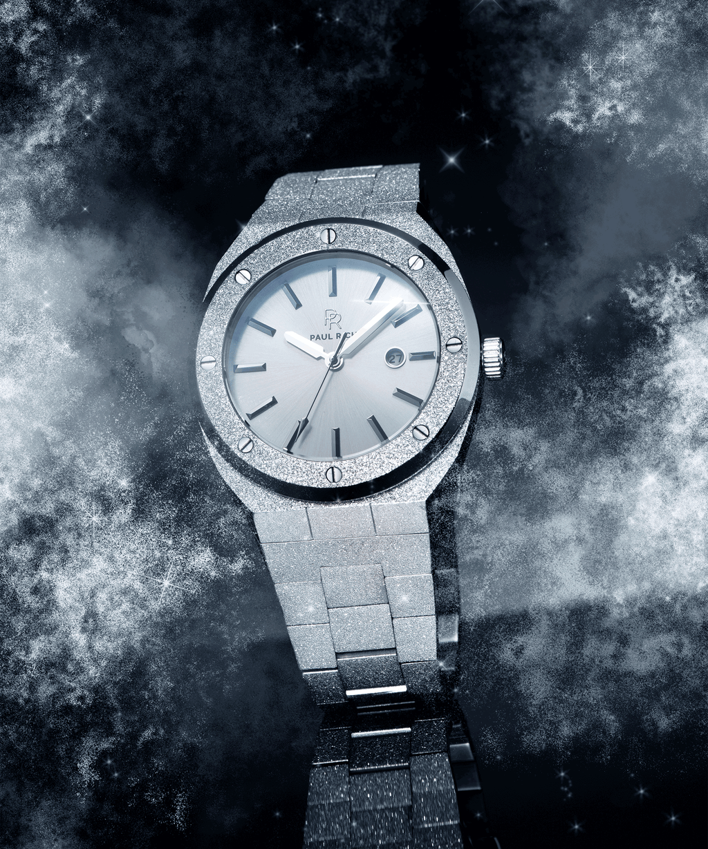 Paul Rich frosted silver watch with metallic dial and date window, shown at an angle against a cosmic background of stars and mist.