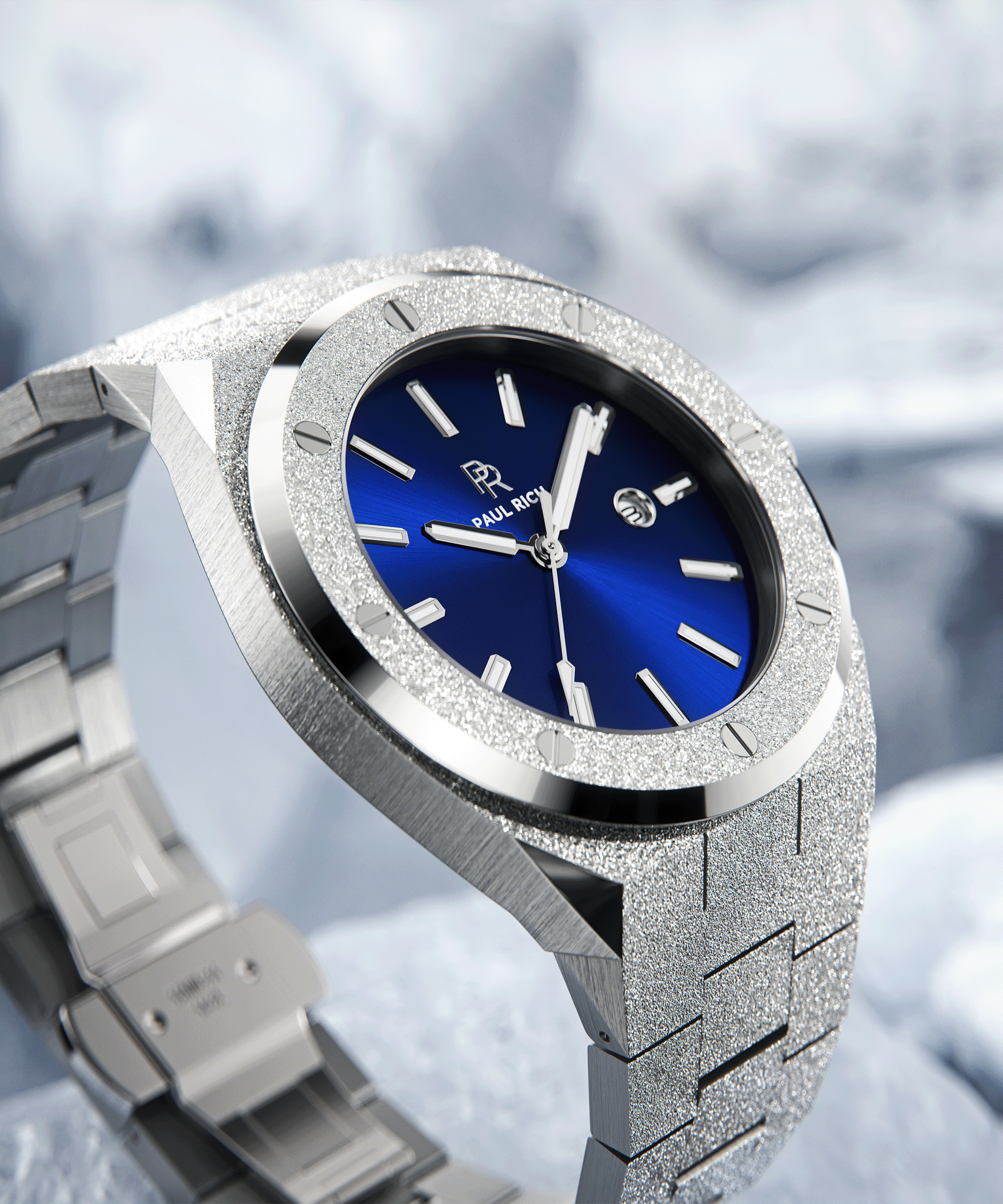 Paul Rich frosted silver watch with metallic blue sunray dial and date window, shown at an angle on icy surface with snowy backdrop.