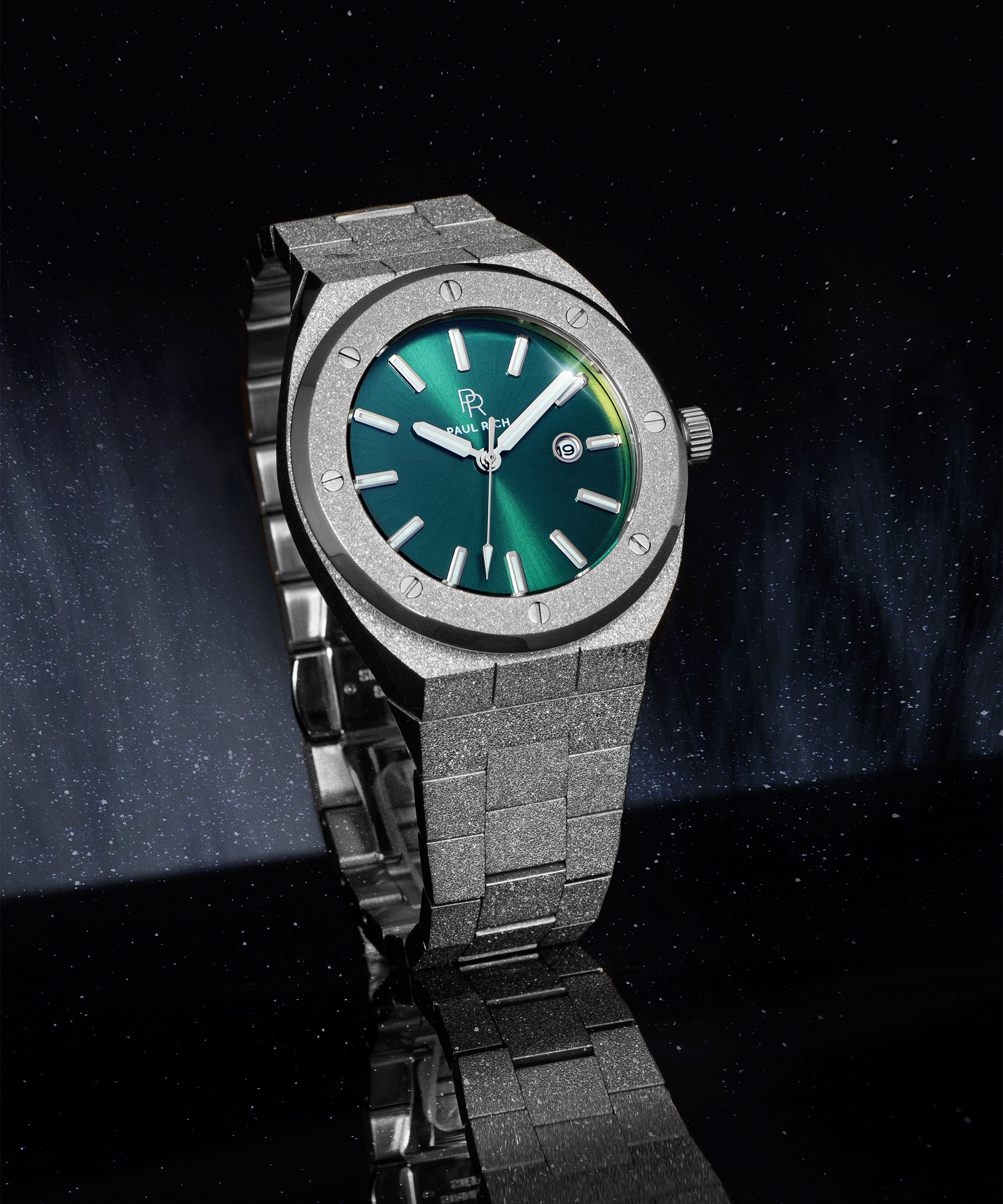 Paul Rich frosted watch with green sunray dial, silver markers, and date window, shown at an angle on a reflective black surface.