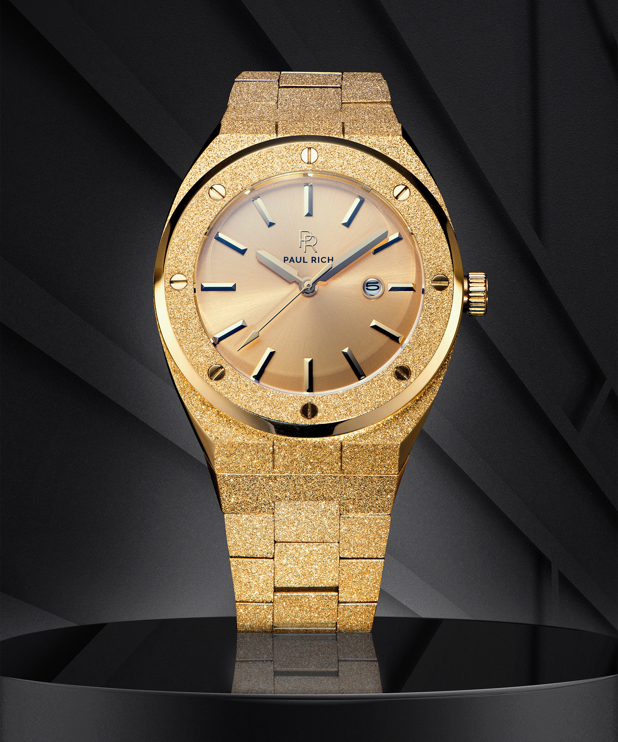 Paul Rich watch with frosted gold case and bracelet, metallic champagne gold sunray dial, and date window, displayed on a black geometric background.