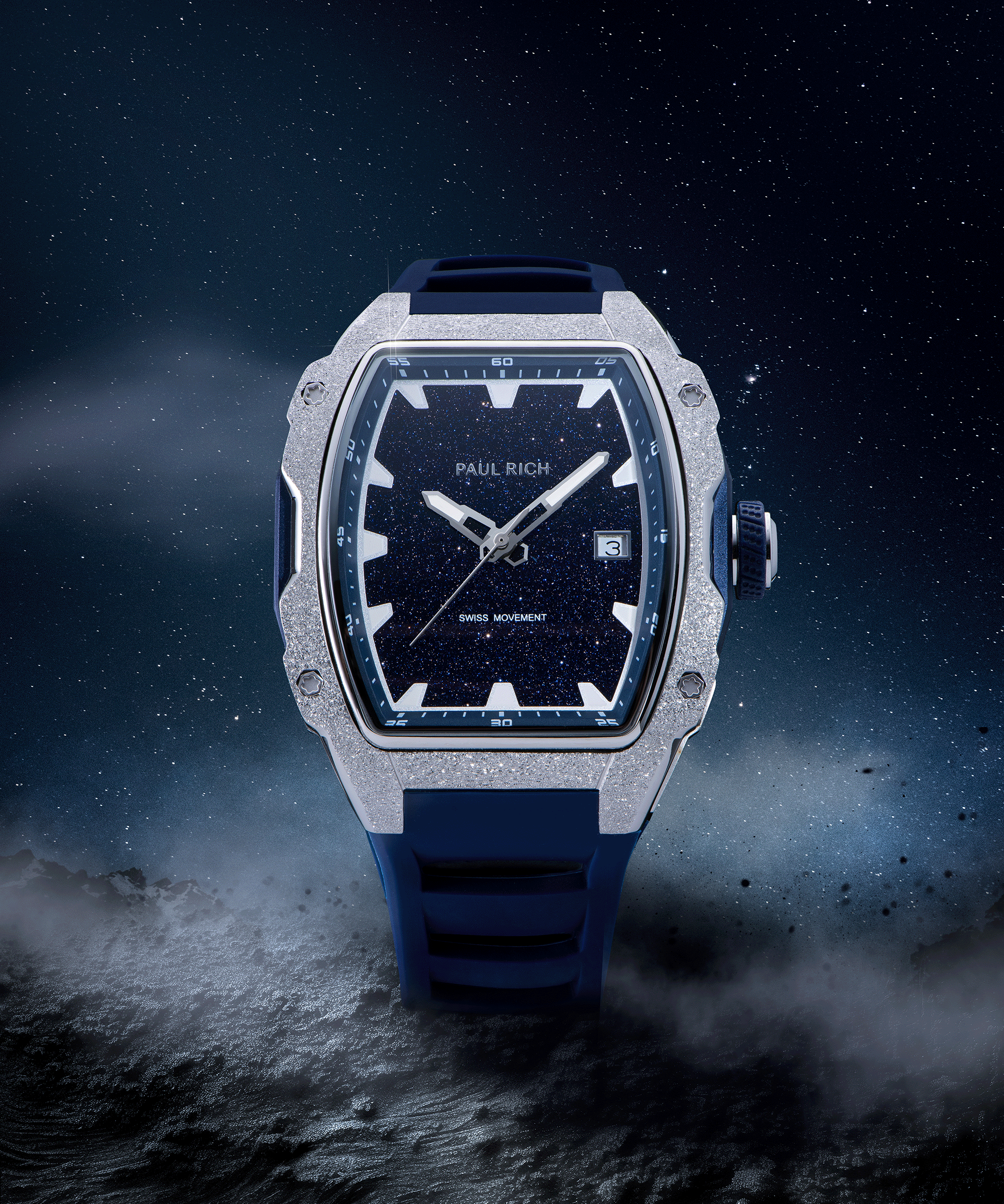Paul Rich watch with tonneau case, frosted silver bezel, blue aventurine dial, and blue strap, shown on a starry cosmic landscape with fog.