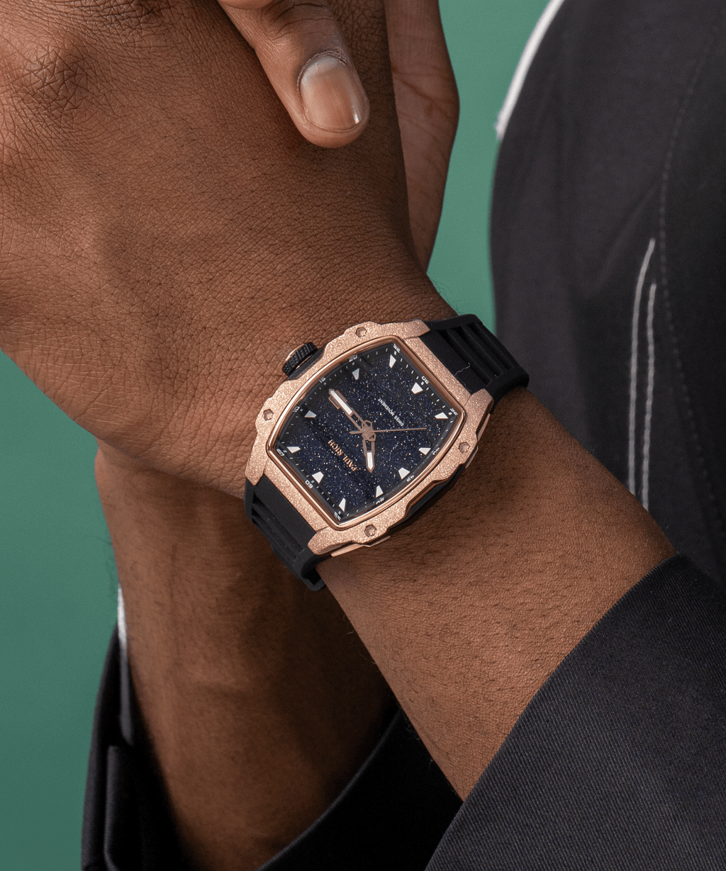 Paul Rich watch with blue aventurine dial and rose gold frosted bezel worn on wrist, paired with black outfit and green backdrop.