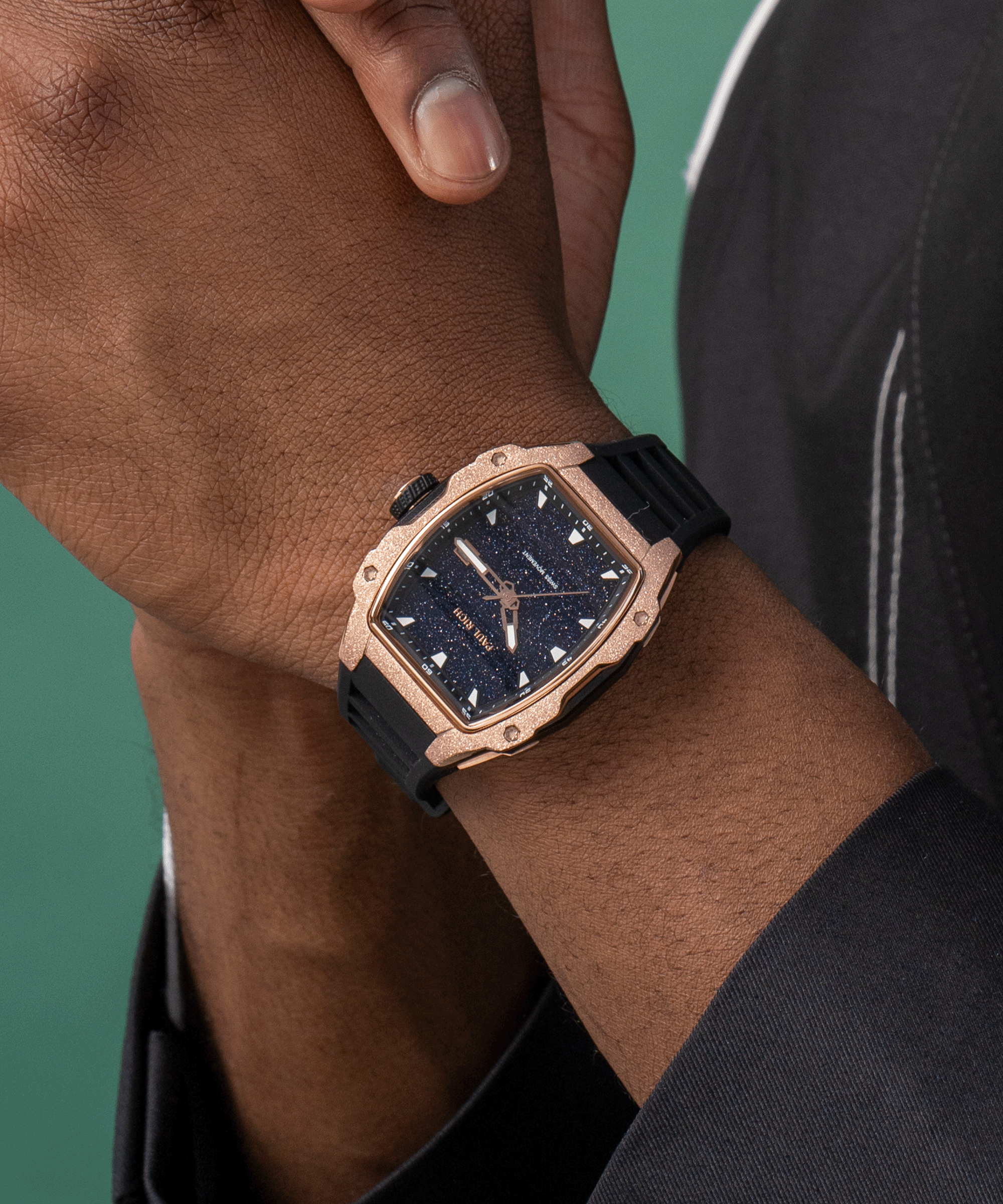 Paul Rich watch with blue aventurine dial and rose gold frosted bezel worn on wrist, paired with black outfit and green backdrop.