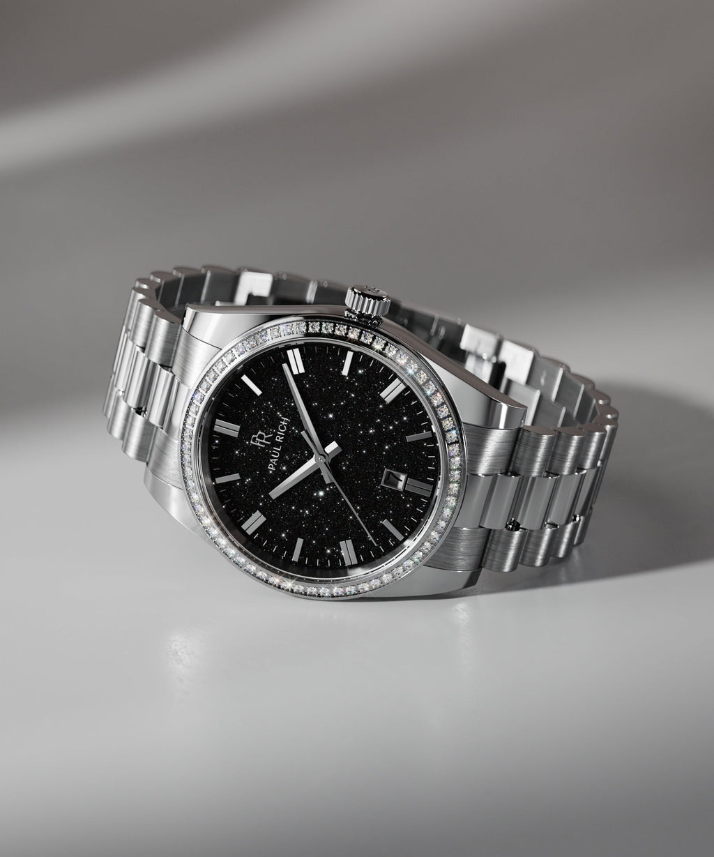 Silver wristwatch with a black aventurine dial, crystal-set bezel, and metal bracelet displayed on a white surface with soft shadowing.