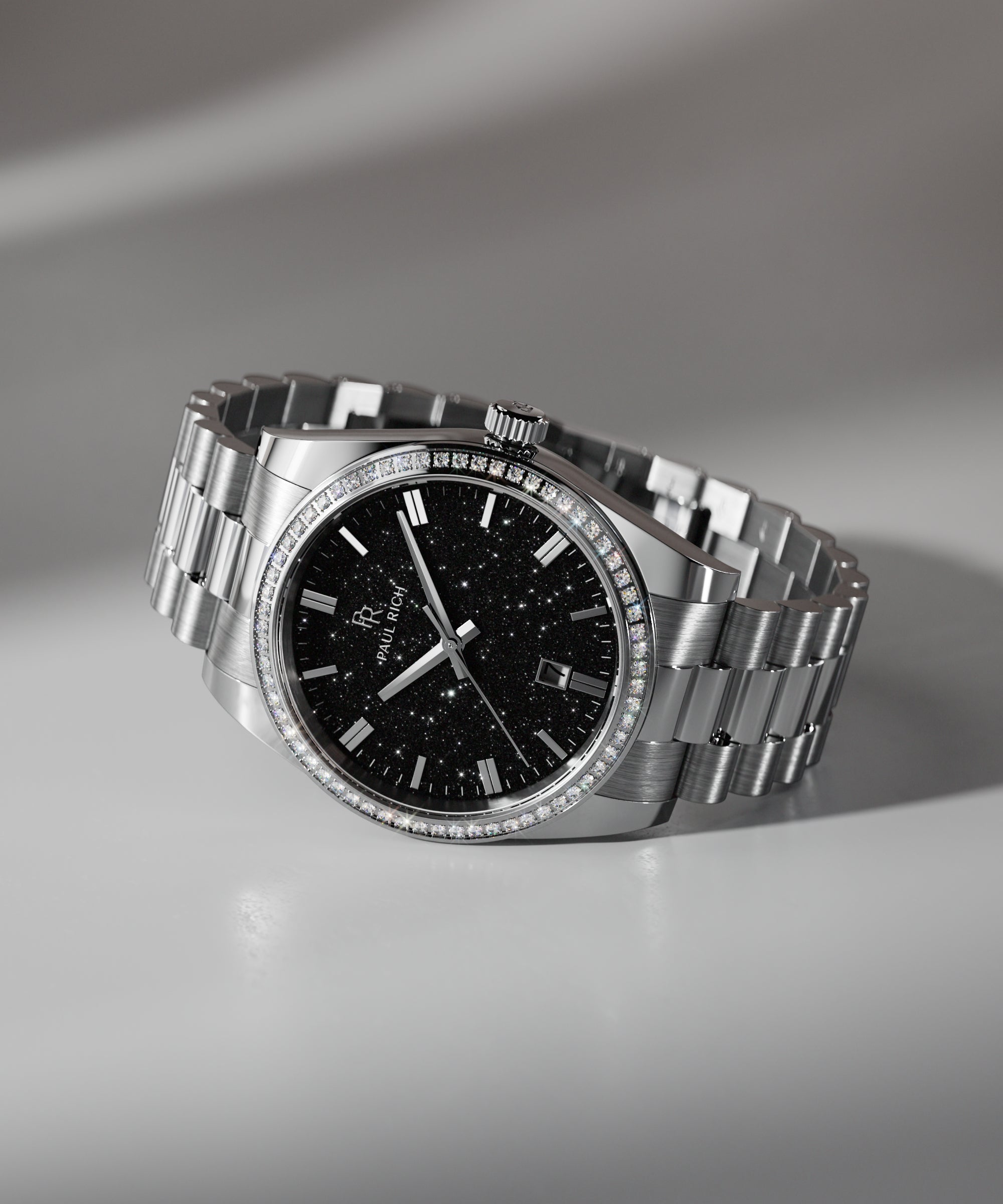 Silver wristwatch with a black aventurine dial, crystal-set bezel, and metal bracelet displayed on a white surface with soft shadowing.
