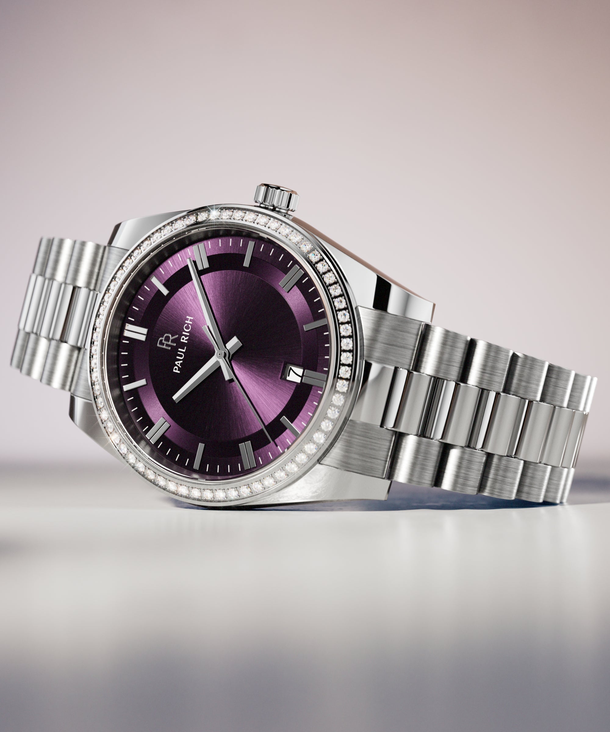 Silver wristwatch with a purple sunburst dial, crystal-set bezel, and metal bracelet displayed on a smooth white surface with soft lighting.