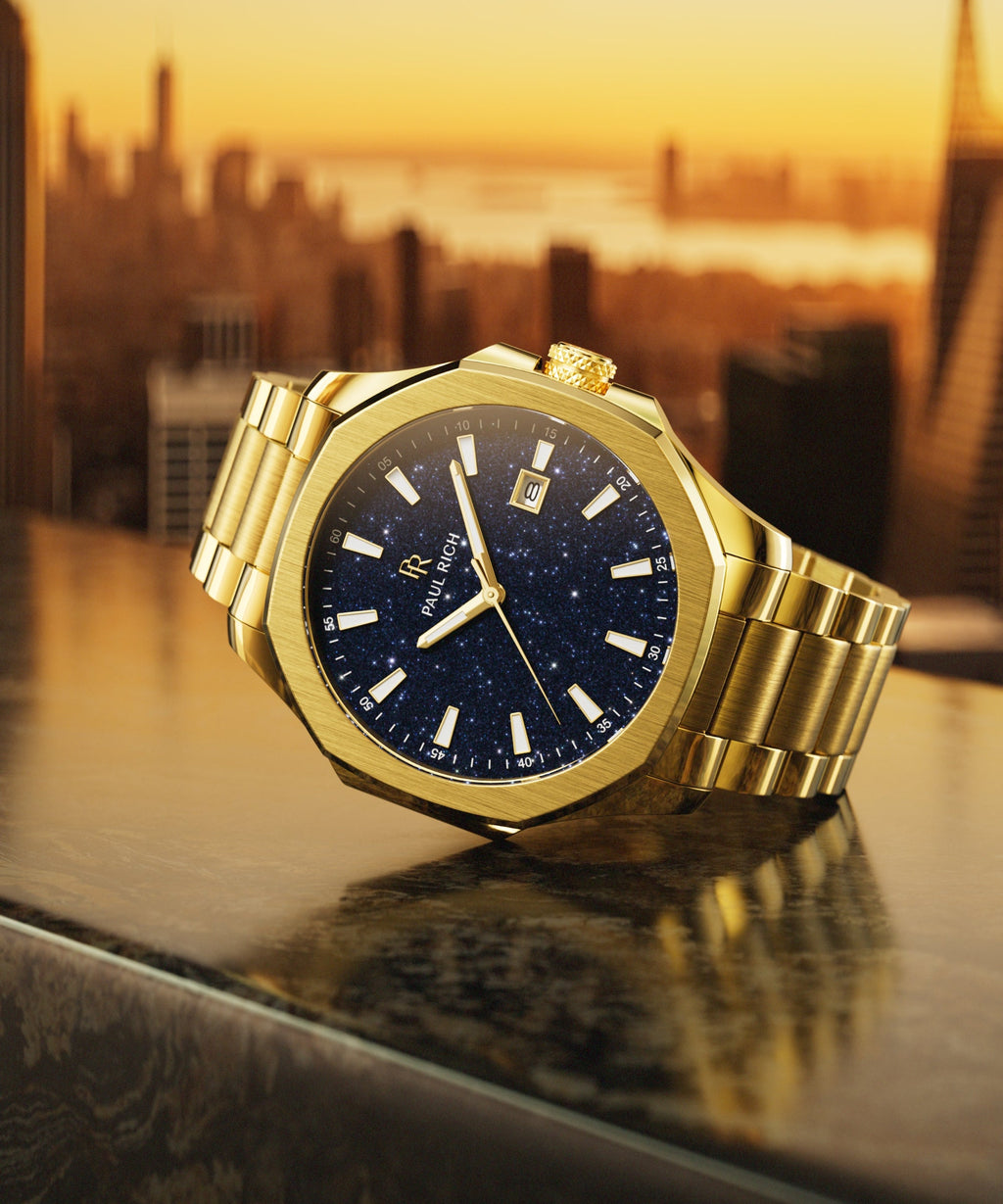 Paul Rich watch with brushed gold case and blue aventurine dial displayed on a rooftop ledge at golden hour, with NYC skyline in background.