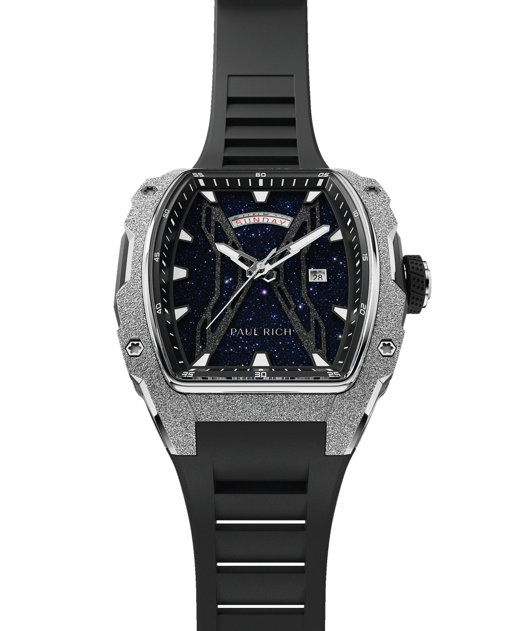 Paul Rich watch shown at an angle with blue aventurine dial, silver frosted bezel, day-date display, and full black rubber strap.