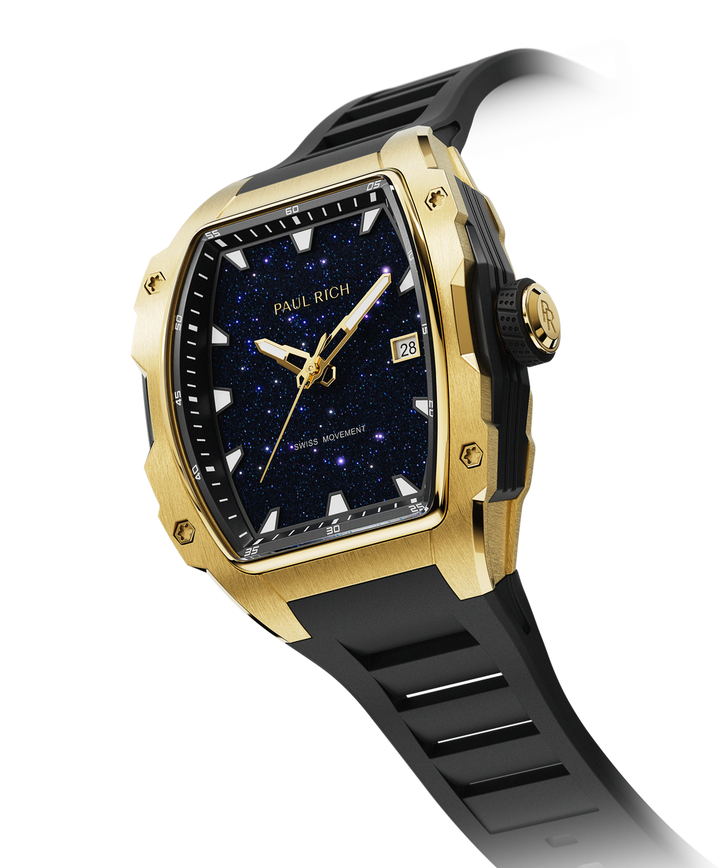Angled view of a Paul Rich gold-tonneau watch with blue aventurine dial, gold-tone hands, date window, and black rubber strap.