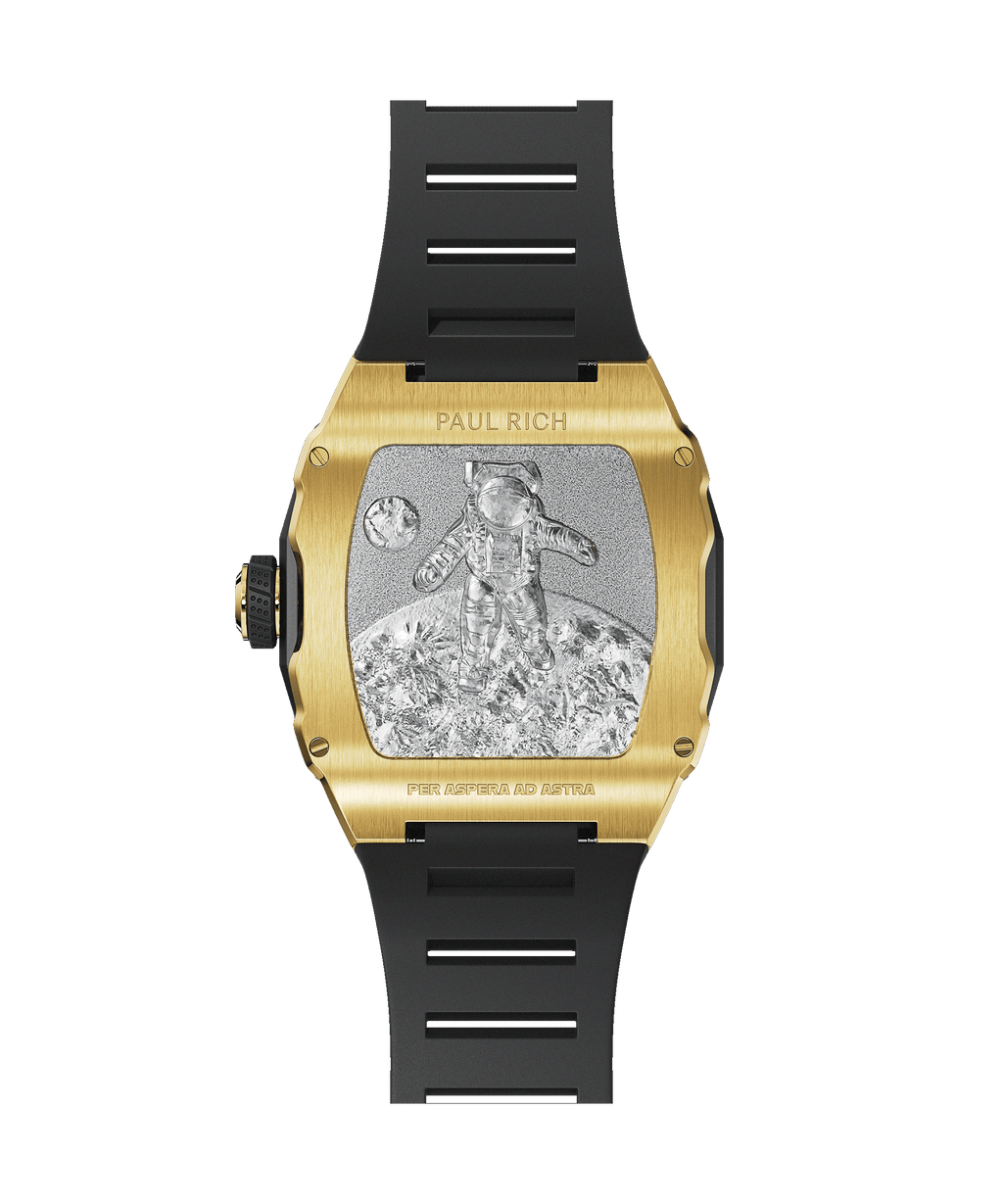 Back view of a Paul Rich gold-tonneau watch with engraved astronaut on the moon, “PER ASPERA AD ASTRA” inscription, and black rubber strap.