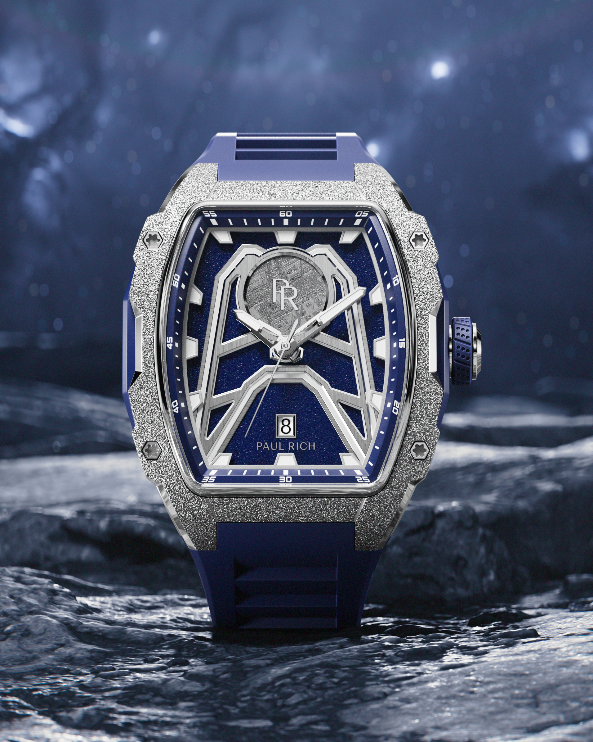 Paul Rich Astro Meteora watch with meteorite inlay, frosted bezel, and navy rubber strap, displayed on a rocky surface under a starry sky.