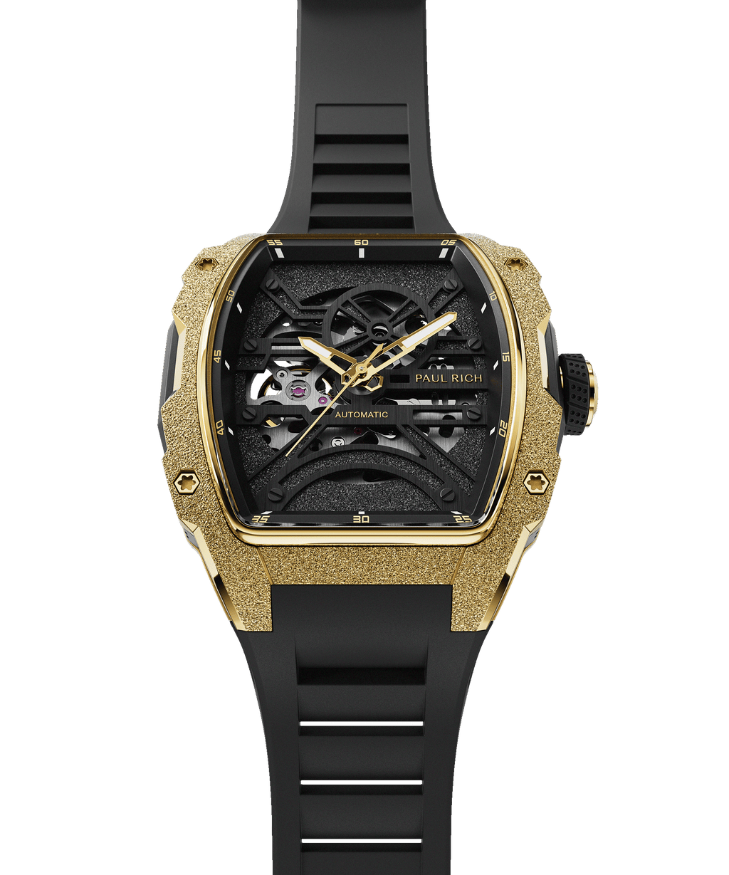 Front view of Paul Rich watch with frosted gold tonneau case, gold hands, black skeleton dial, and black rubber strap, shown vertically.