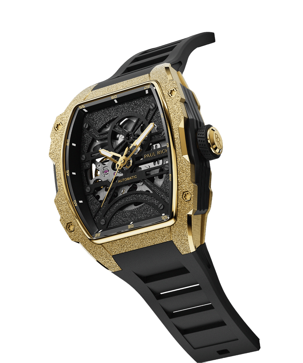 Angled view of Paul Rich watch with frosted gold tonneau case, skeleton dial, and black rubber strap, shown on transparent background.