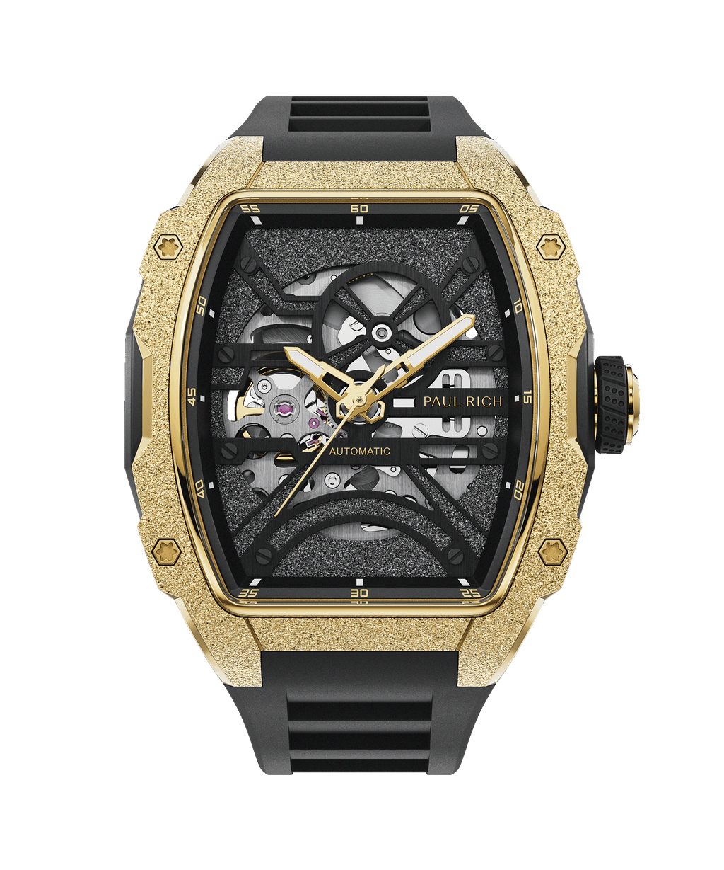 Paul Rich watch with frosted gold tonneau case, skeleton dial, gold hands, and black rubber strap, shown on transparent background.