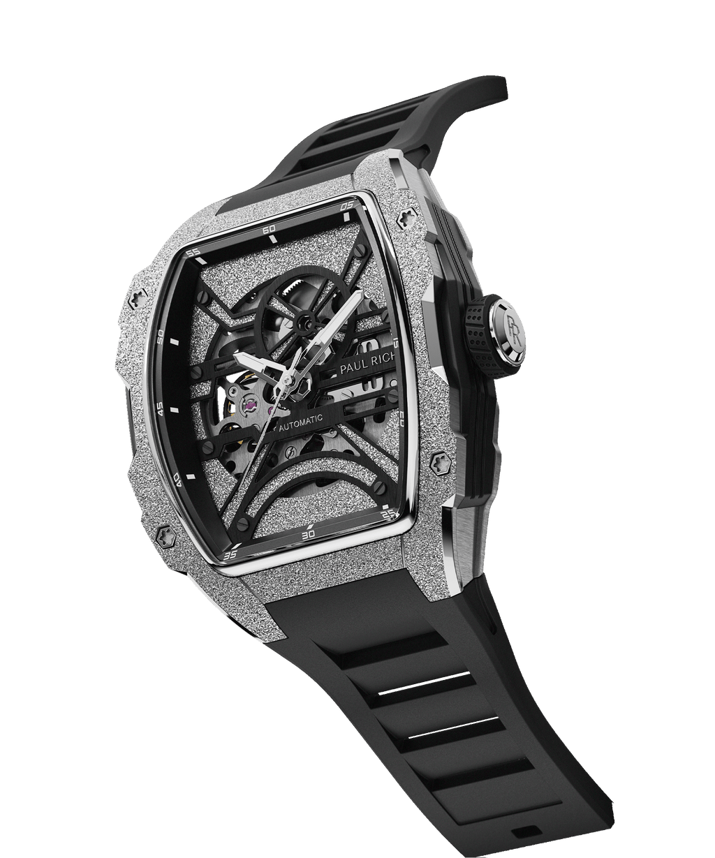 Angled view of Paul Rich watch with frosted silver tonneau case, skeleton dial, white hands, and black rubber strap, shown on transparent background.