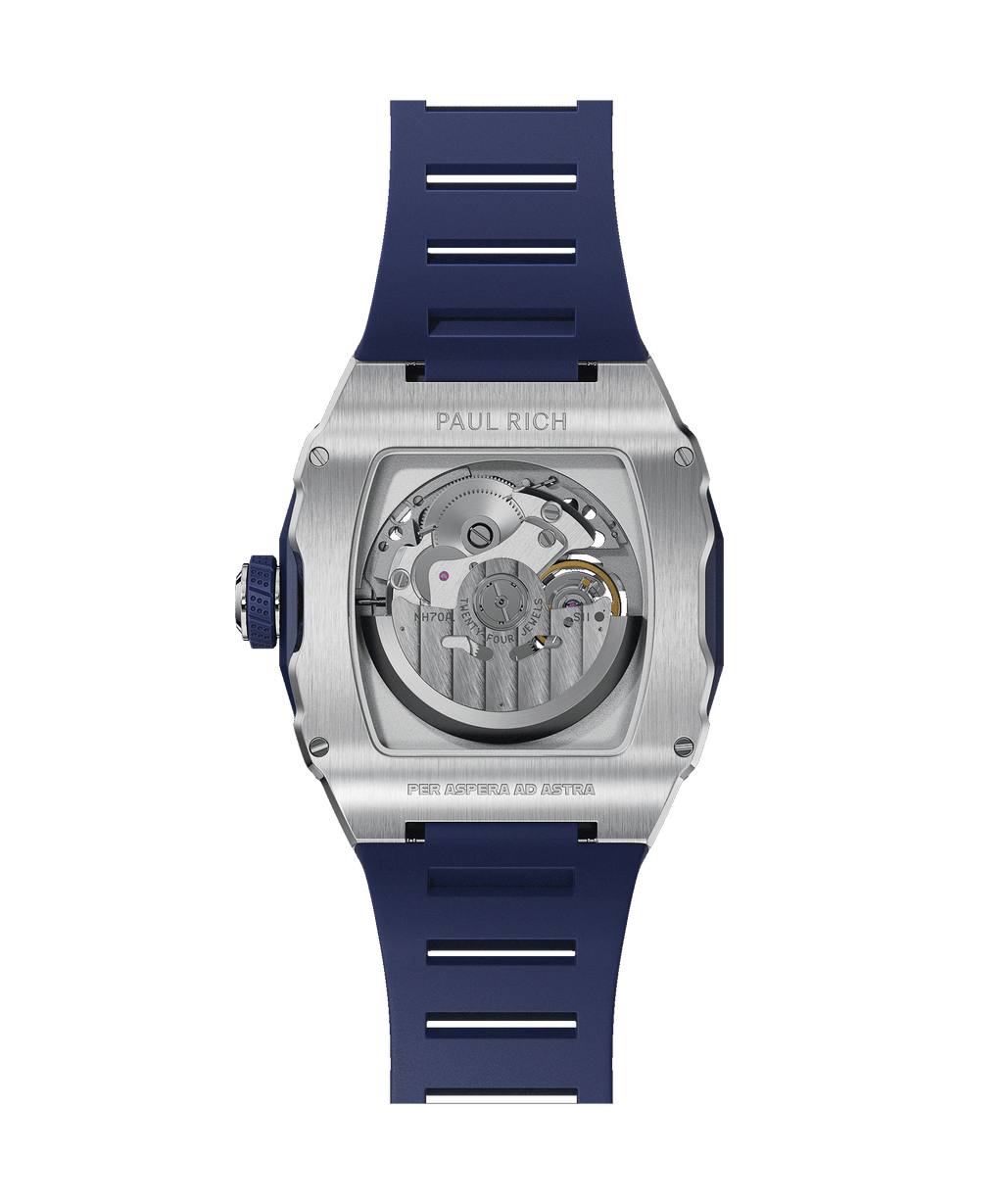 Back view of Paul Rich watch with brushed silver case, visible automatic movement, and blue rubber strap, engraved with ‘Per Aspera Ad Astra.’