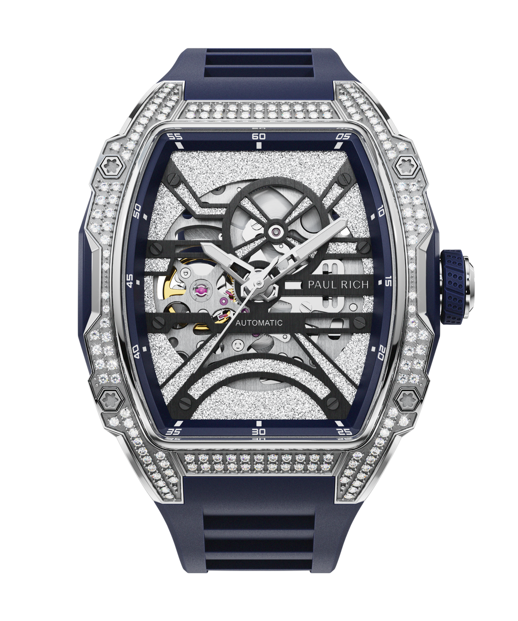 Close-up front view of open dial watch with diamond-set silver case and navy blue strap, shown on transparent background.