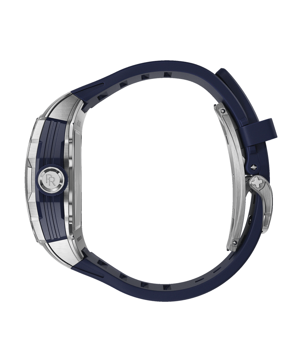 Side view of Paul Rich watch with brushed silver and blue case, PR monogram crown, and blue rubber strap, shown on transparent background.