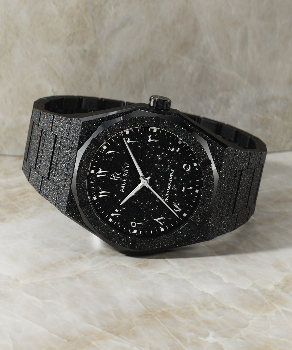 Paul Rich black frosted watch with black aventurine dial and silver Eastern Arabic numerals, displayed horizontally on marble surface.