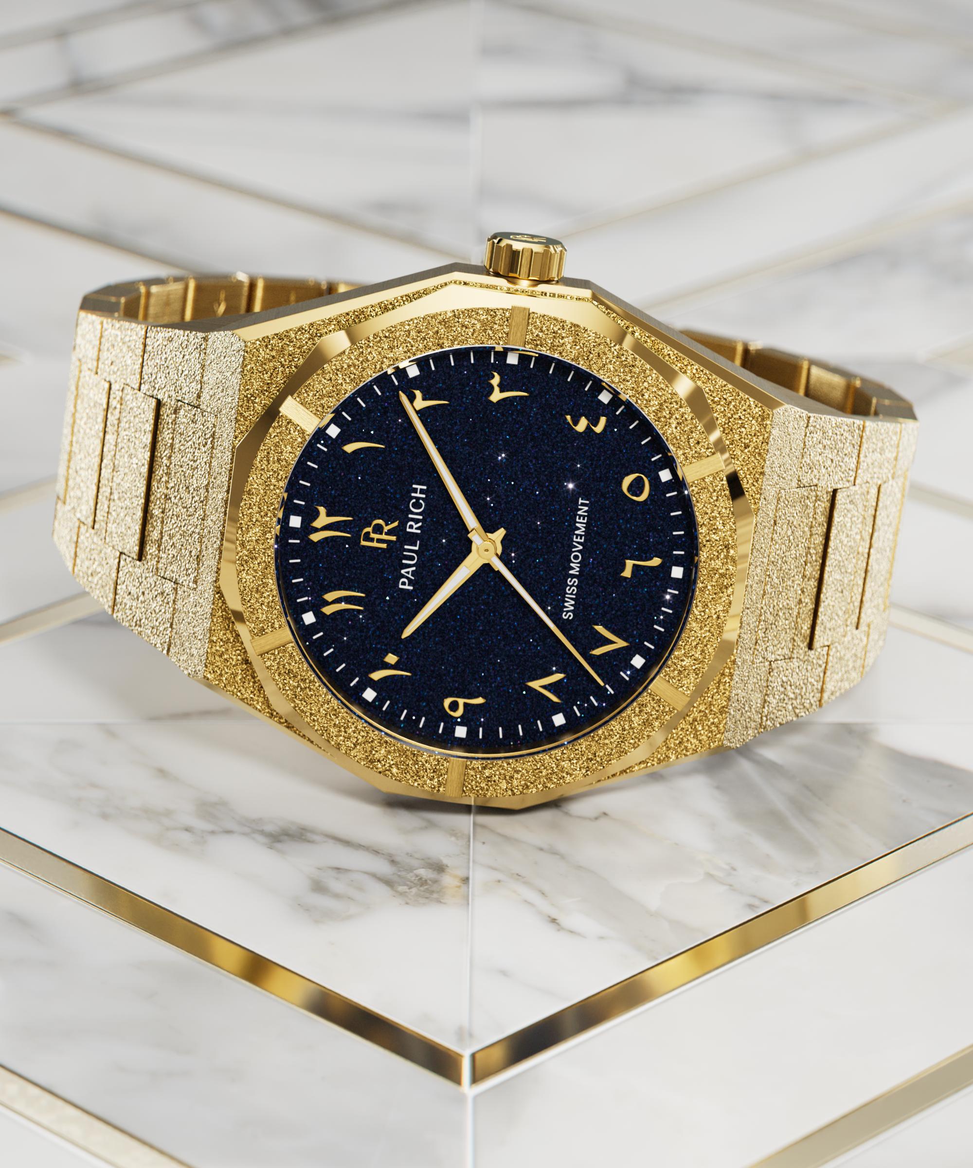 Frosted gold watch with blue aventurine dial and Arabic numerals, displayed on a white marble surface with gold geometric accents.