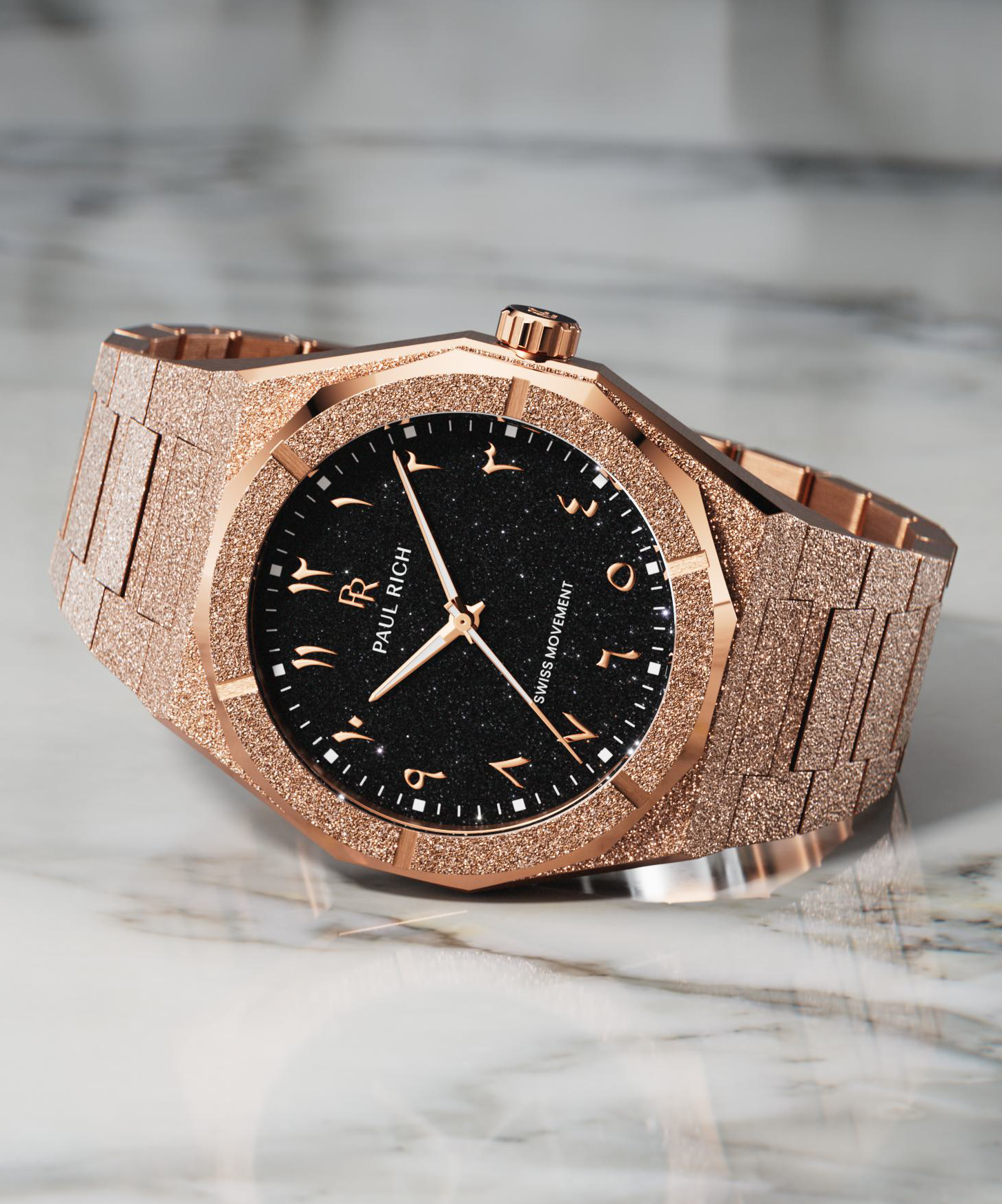 Rose gold wristwatch with a frosted textured case and bracelet, black aventurine dial, and Arabic numerals, displayed on a white marble surface.