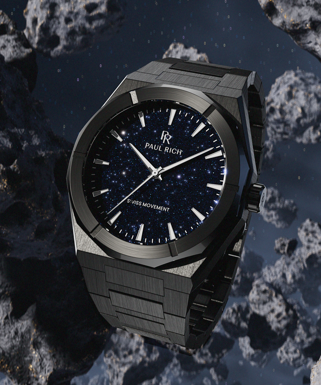 Black Paul Rich watch with blue aventurine dial displayed among floating asteroids in deep space, with starry sky in the background.