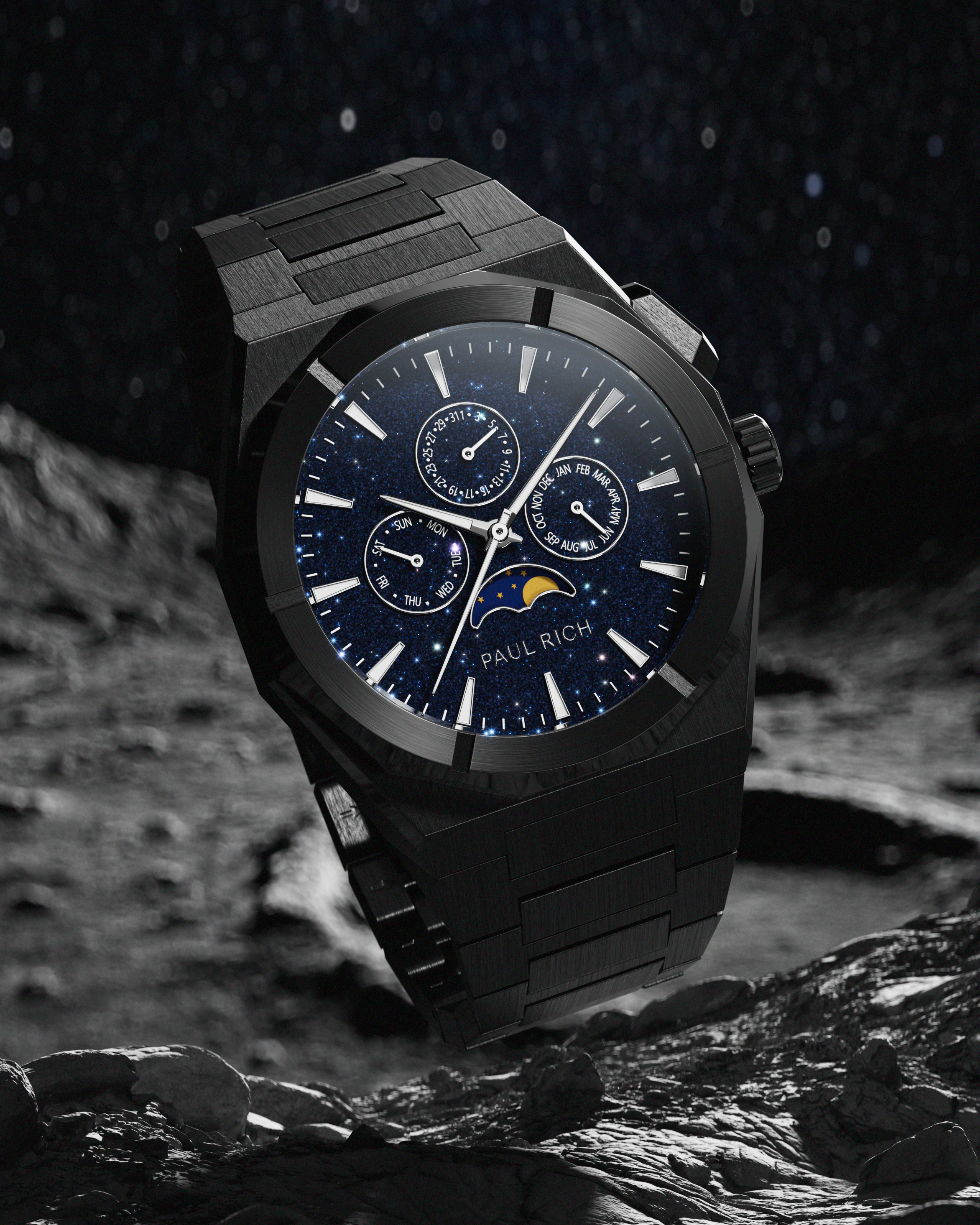 Brushed black stainless steel watch with blue aventurine dial, moonphase, and subdials, set against a rocky lunar surface and star-filled sky.