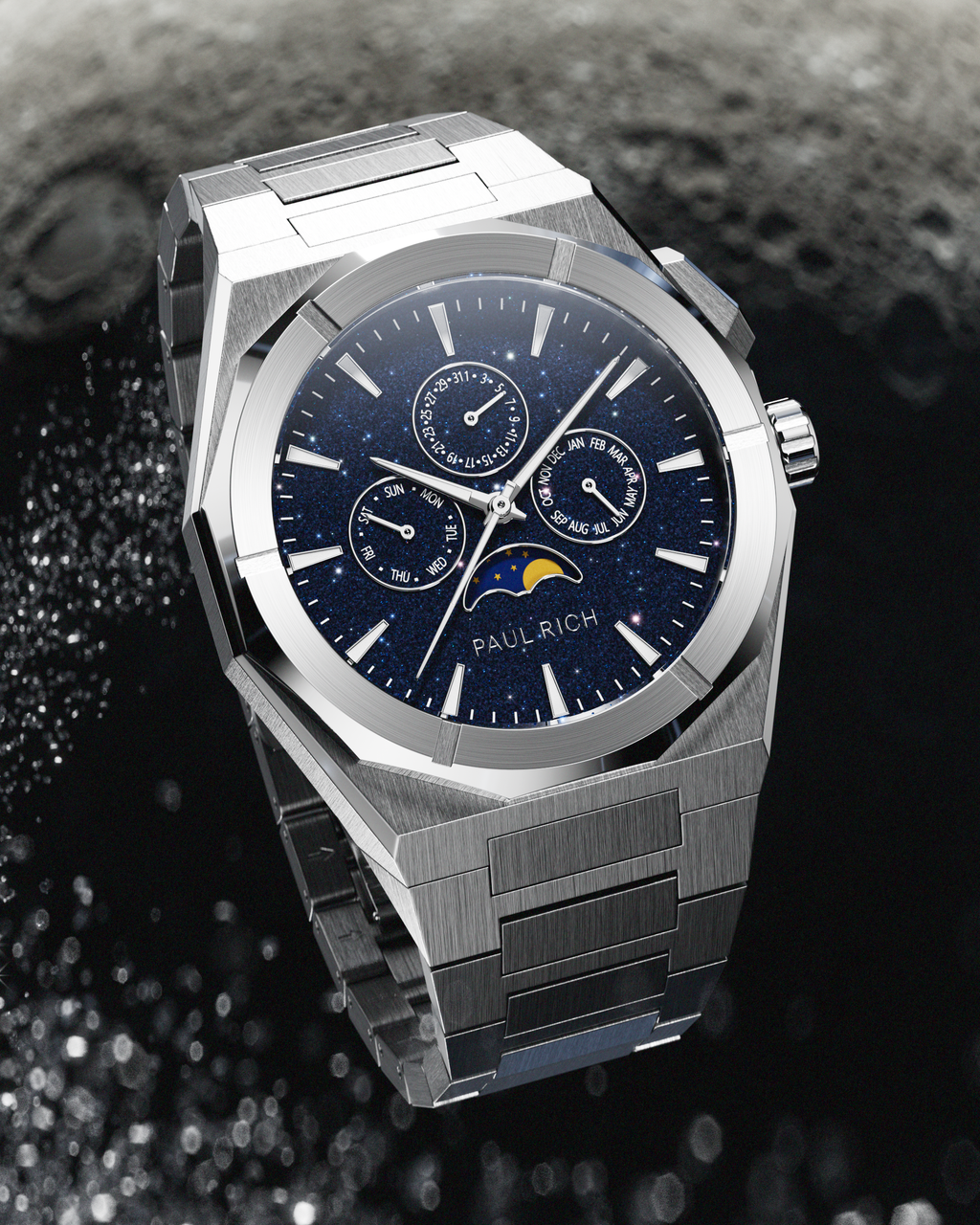 Brushed silver stainless steel watch with blue aventurine dial, moonphase, and subdials, displayed against a textured black and grey lunar surface backdrop.