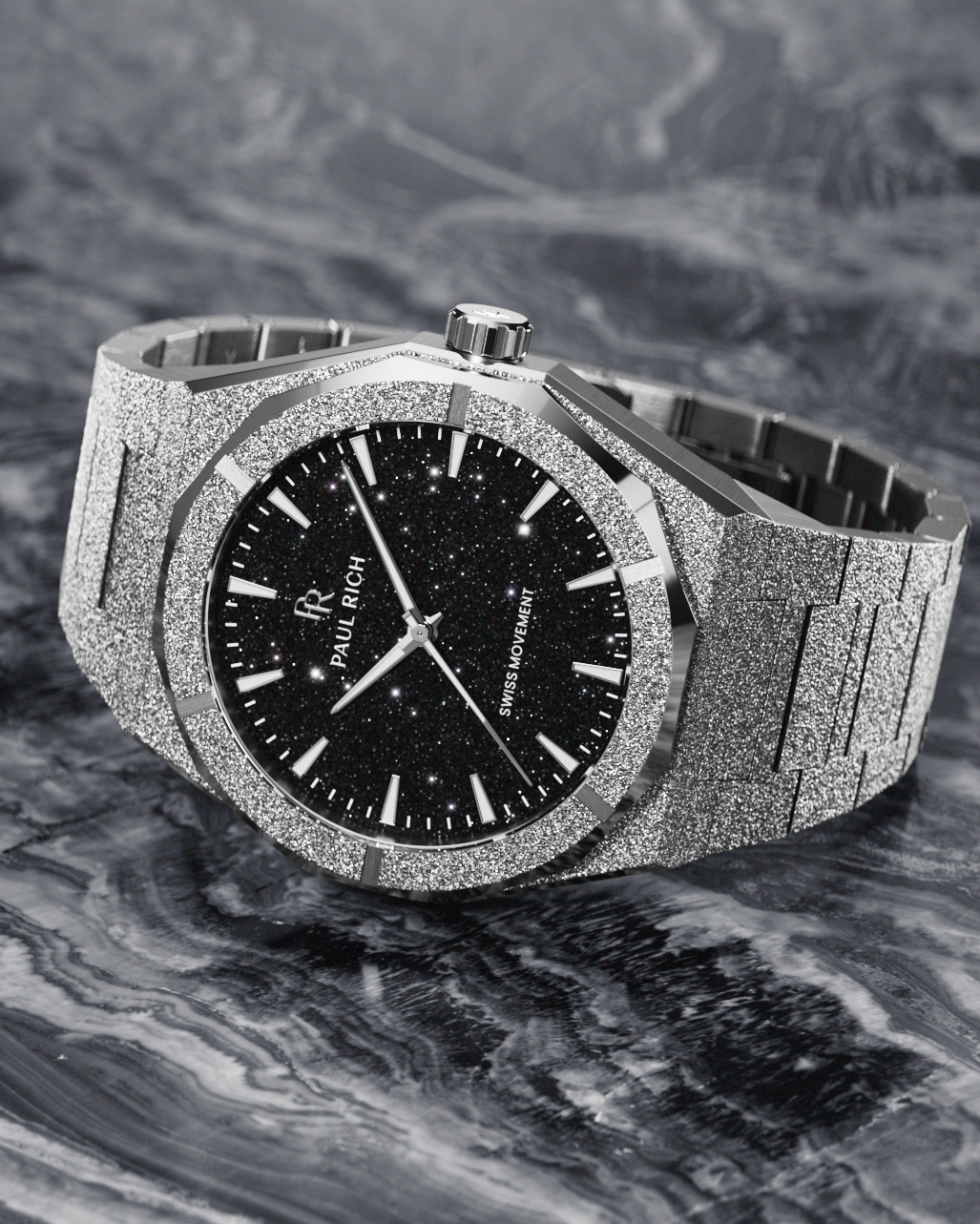 Paul Rich watch with frosted silver case and black aventurine dial, resting on a marbled surface with swirling monochrome texture.