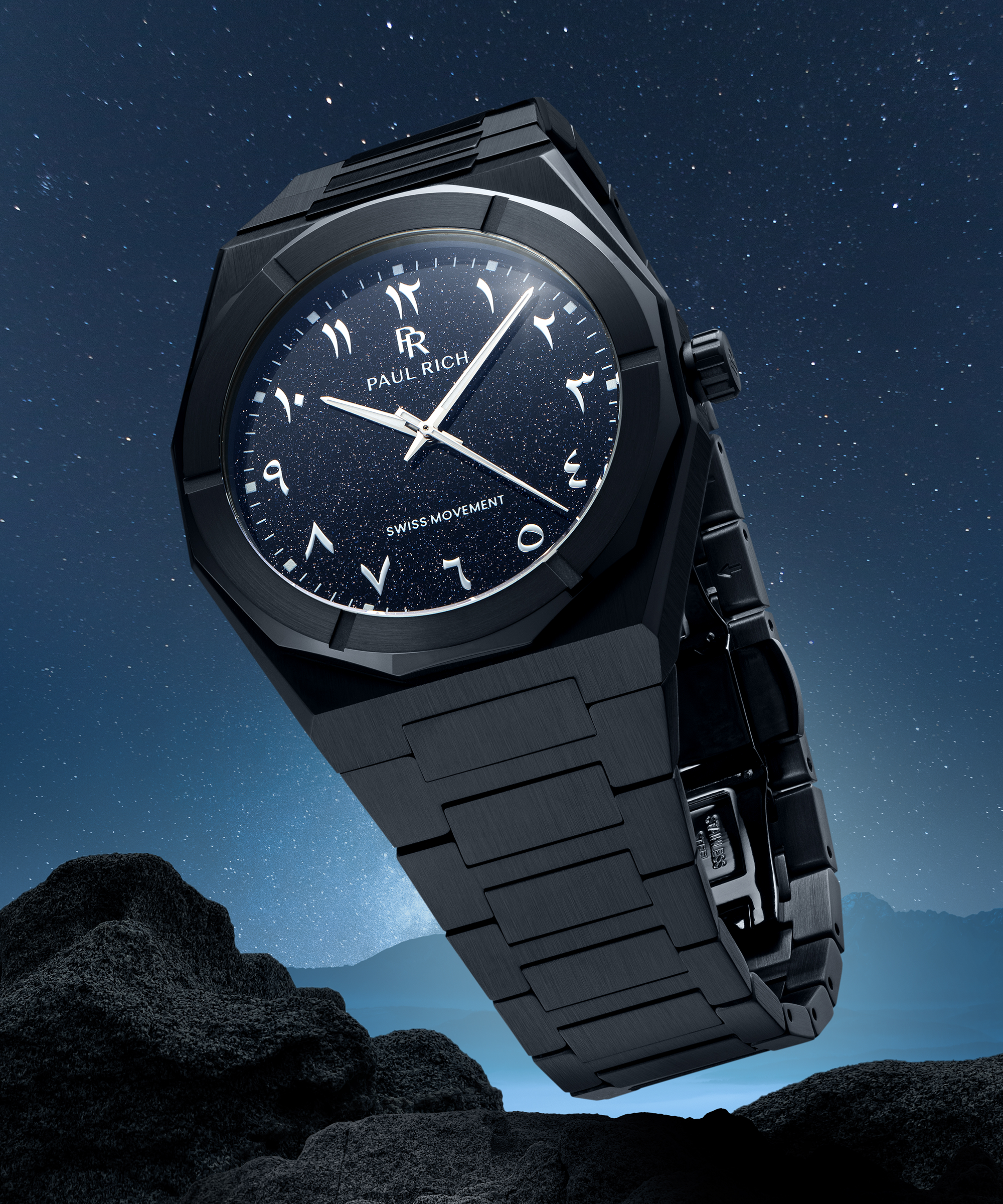 Paul Rich watch with brushed black case and blue aventurine dial with Arabic numerals, displayed above rocky terrain under a starry sky.