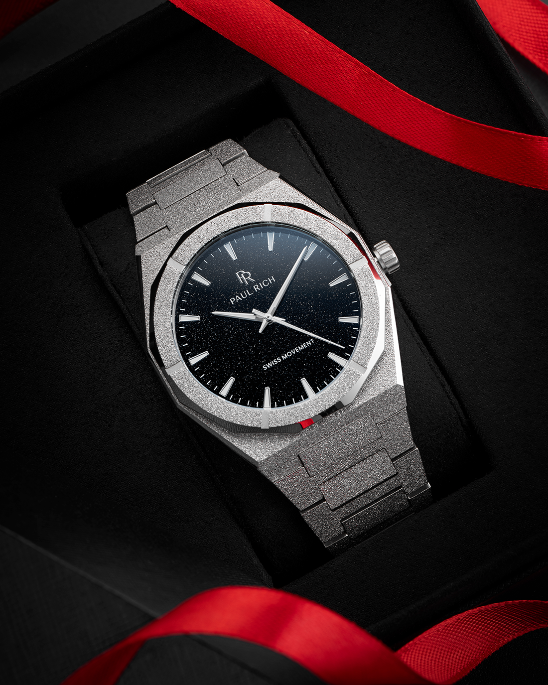 Paul Rich watch with frosted silver case and black aventurine dial, presented in a black gift box with red ribbon accents.