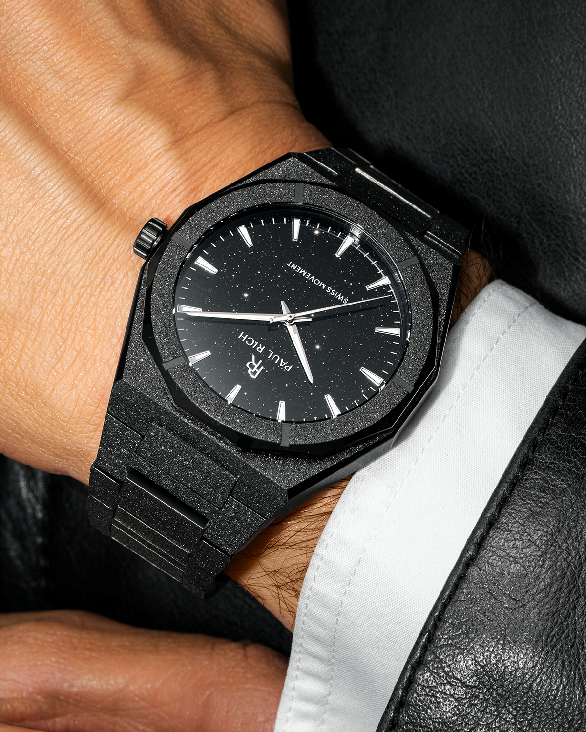 Paul Rich watch with frosted black case and black aventurine dial, worn with a white cuff and black leather jacket.