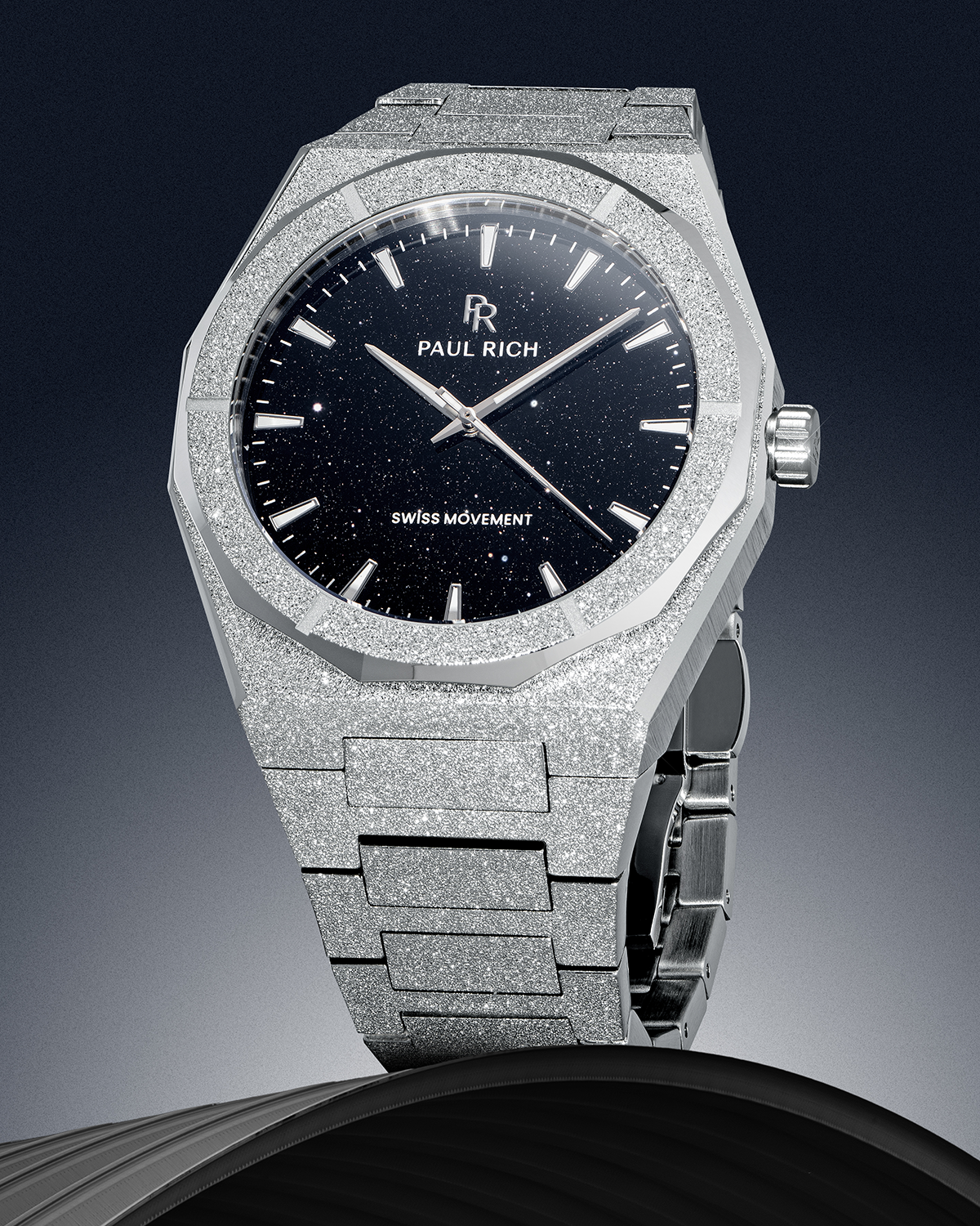 Paul Rich watch with frosted silver case and black aventurine dial, displayed vertically against a gradient background on a dark sculpted base.