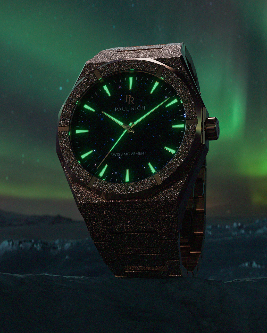 Dark frosted Paul Rich watch with glowing green hands and markers, set against aurora-lit night sky over icy landscape.