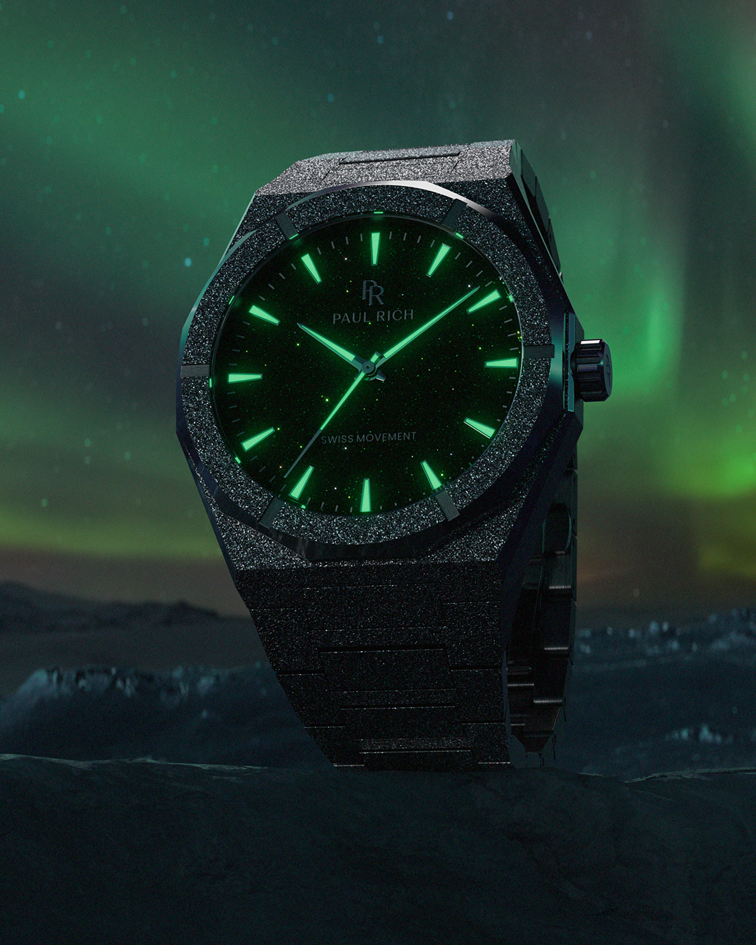 Black frosted Paul Rich watch with glowing green hands and markers, set against a dark arctic landscape and vivid aurora sky.