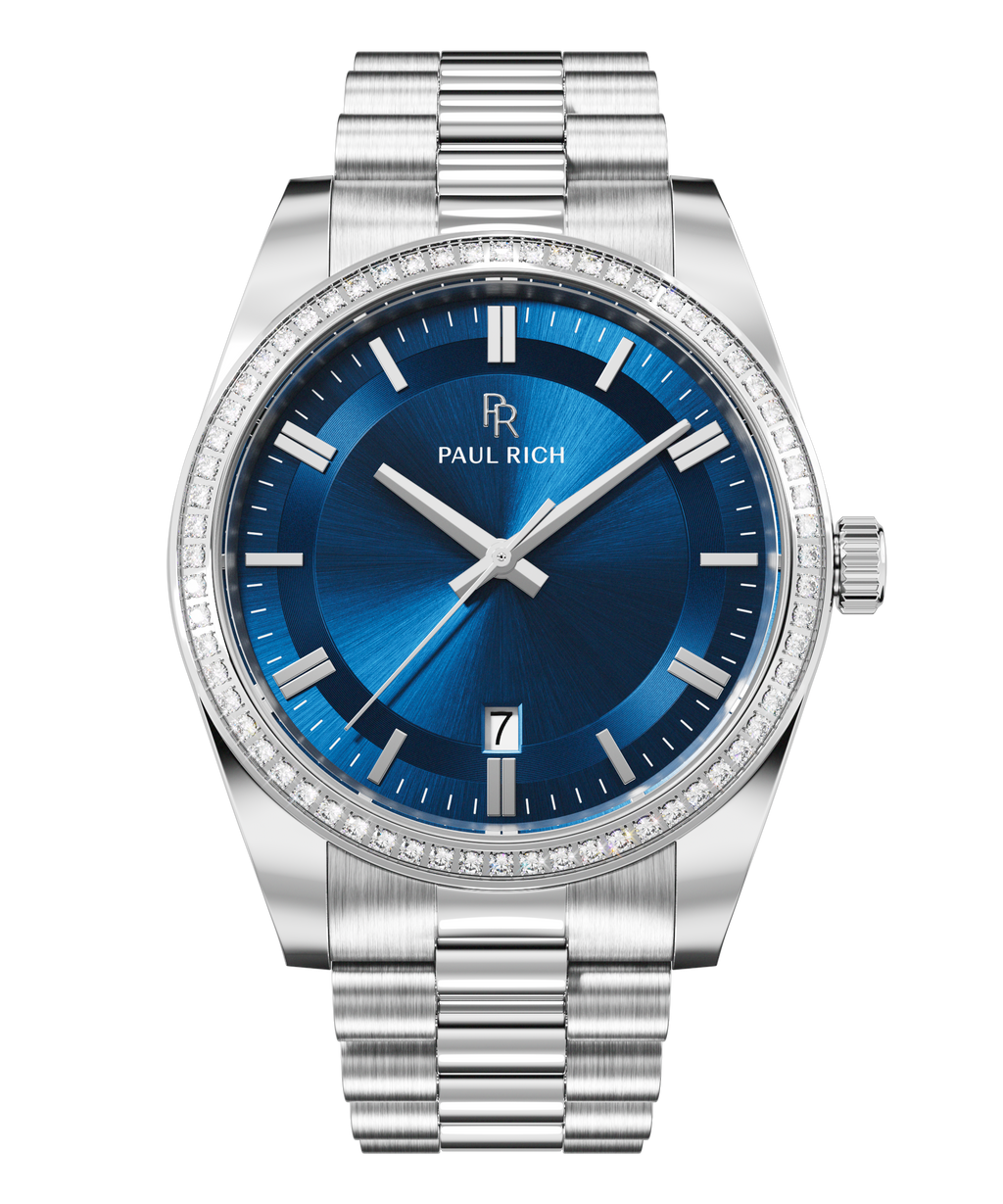 Front view of a silver-tone Paul Rich watch with deep blue sunray dial, diamond-set bezel, silver hour markers and hands, date display at 6 o'clock, and silver link bracelet.